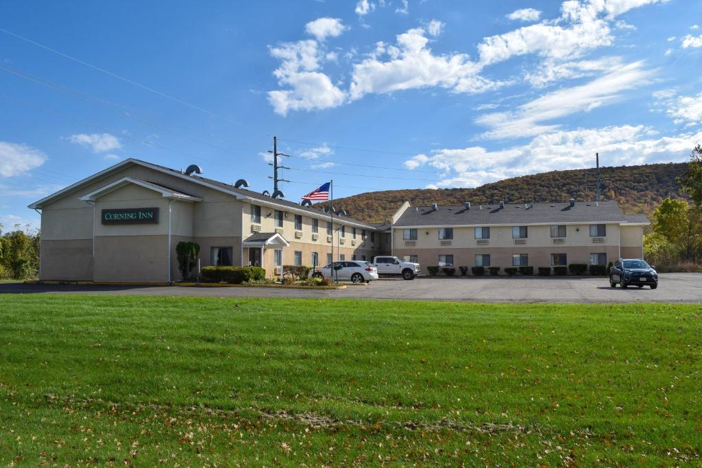 Corning Inn exterior and parking lot, with wooded hills behind